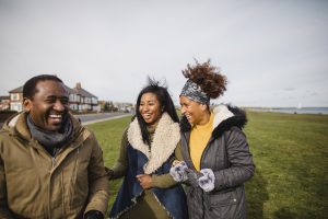 One man and two women on a walk by the sea. 