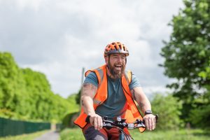 A cyclist wearing a reflective waistcoat while on a bicycle ride. 