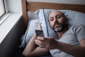 Man in bed on his phone
